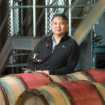 Winemaker in a barrel room with a glass of red wine